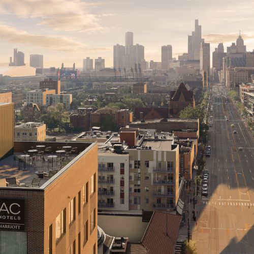 A city skyline at sunset with high-rises, a long street, and nearby hotel rooftops and buildings stretching into the distance.